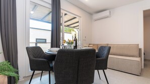 Un salon moderne avec un coin repas, comprenant un canapé, deux fauteuils, une table à manger dressée avec des assiettes, des verres et une bouteille.