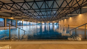 Une piscine intérieure dotée d’un plafond haut et de grandes fenêtres.
