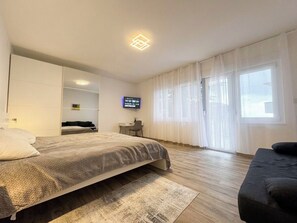 A modern hotel room with a bed, a desk, a chair, and a television. - Apartment Visnja (Crikvenica)