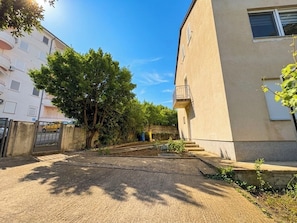 Ein Gebäude mit einem Balkon, einem verschlossenen Eingang und einem Baum im Vordergrund.