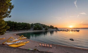 Ein Strand mit Booten, einem Sonnenuntergang und ruhiger See.