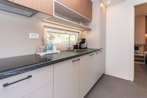 Eine moderne Küche mit schwarzer Arbeitsplatte, weißen Schränken, einem Fenster und einer Kaffeemaschine.