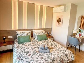 Une chambre d’hôtel comprenant un lit, un bureau, une chaise, une table de chevet, une lampe, une horloge et un miroir.