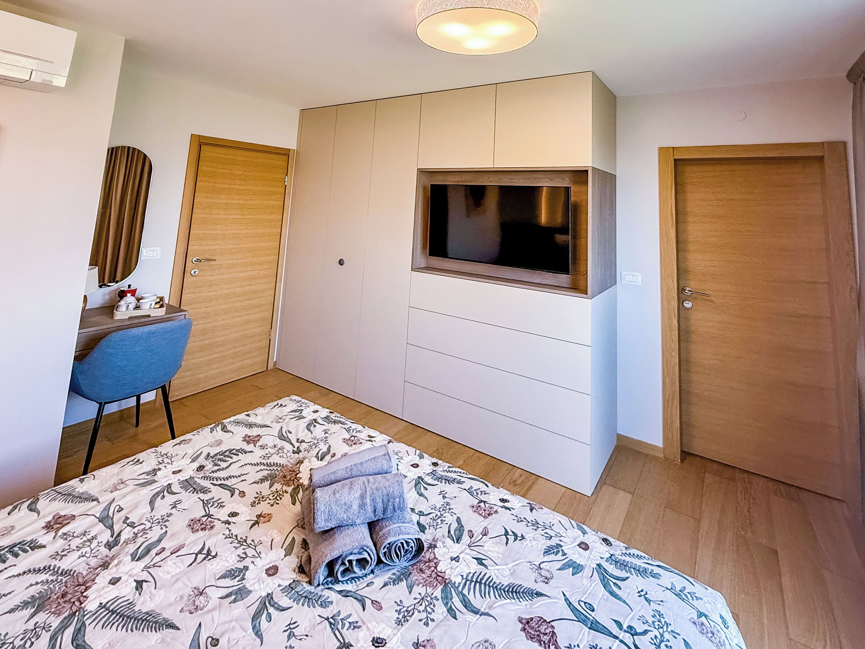 Een slaapkamer met een bed, een bureau, een televisie en een kledingkast.