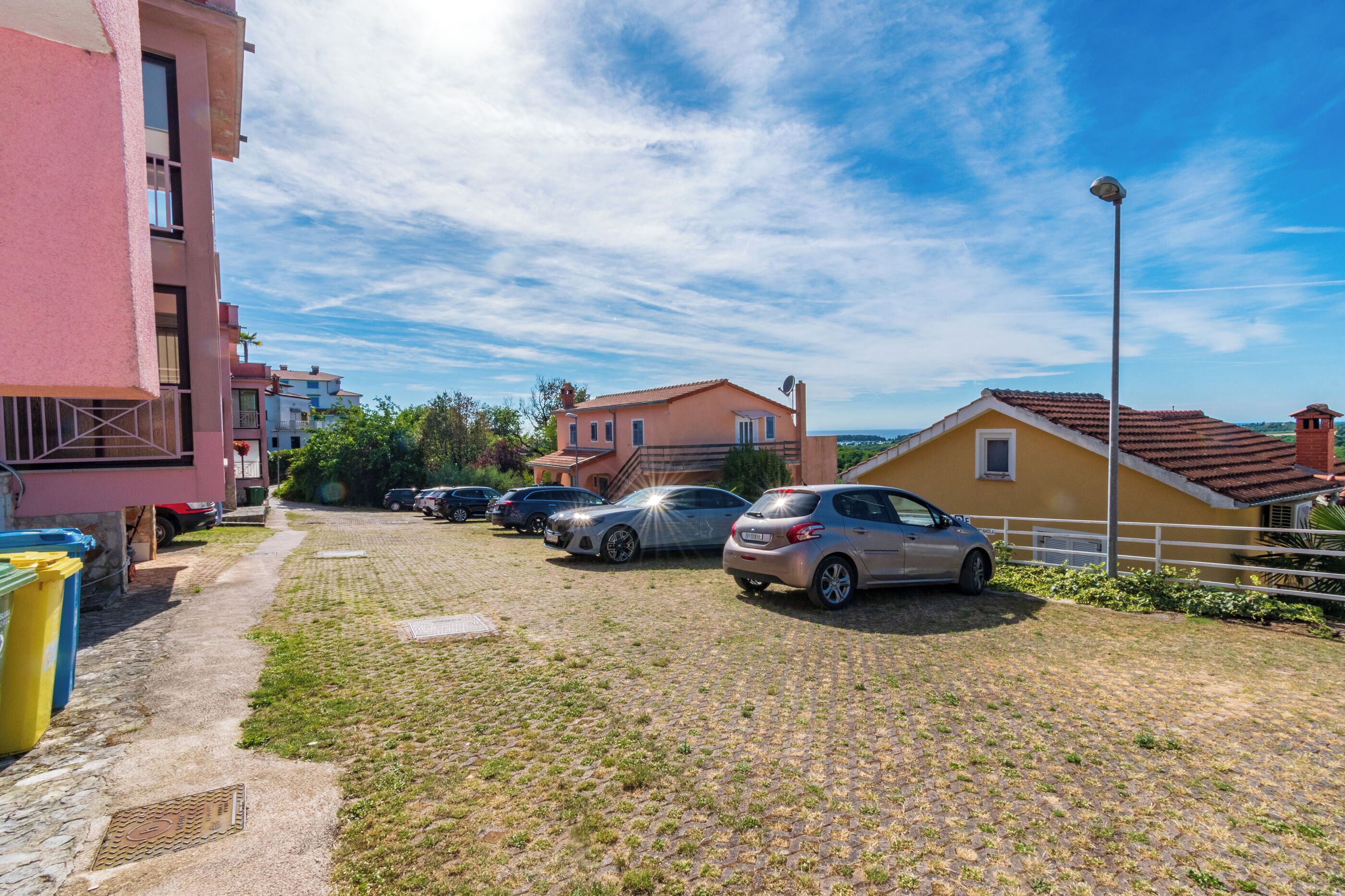 Un quartier résidentiel avec des voitures garées, une allée pavée et des immeubles dotés de balcons.