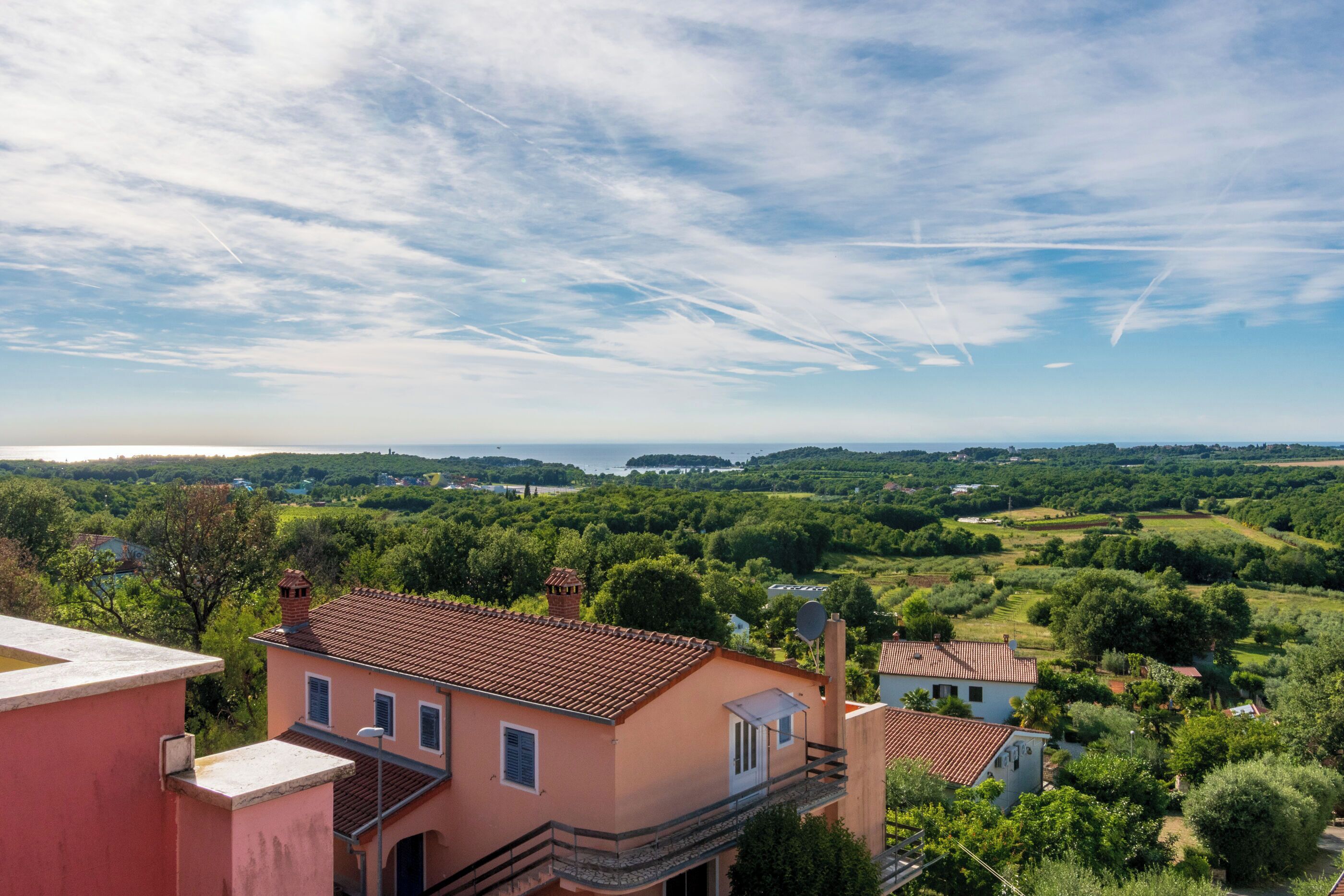 A residential area with houses, a clear sky, and a distant view of a body of water.