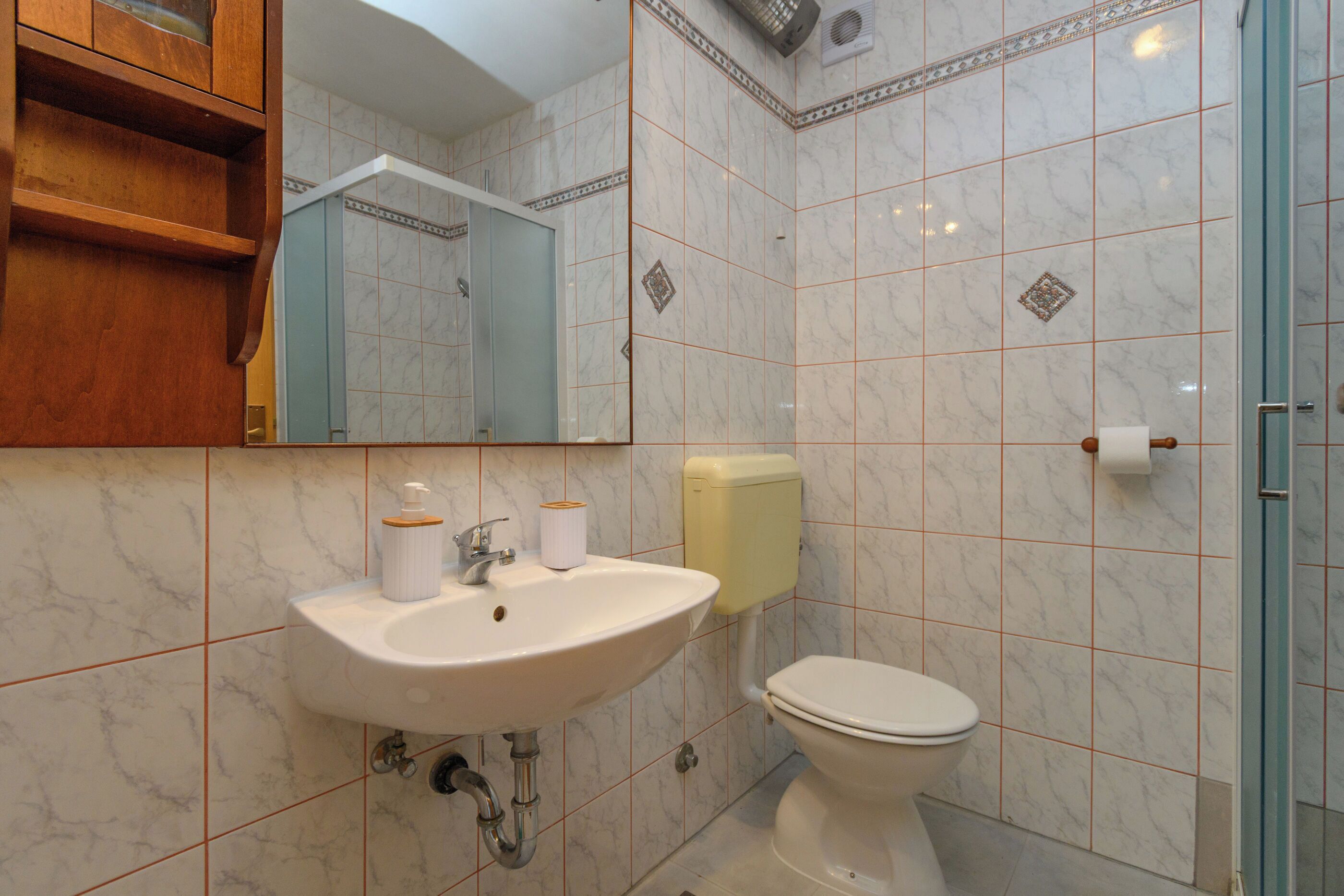 Een badkamer met een wastafel, toilet en spiegel.