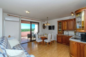Eine moderne Küche mit Holzausstattung, ein Essbereich mit Tisch und Stühlen sowie eine Sitzecke mit Sofa.