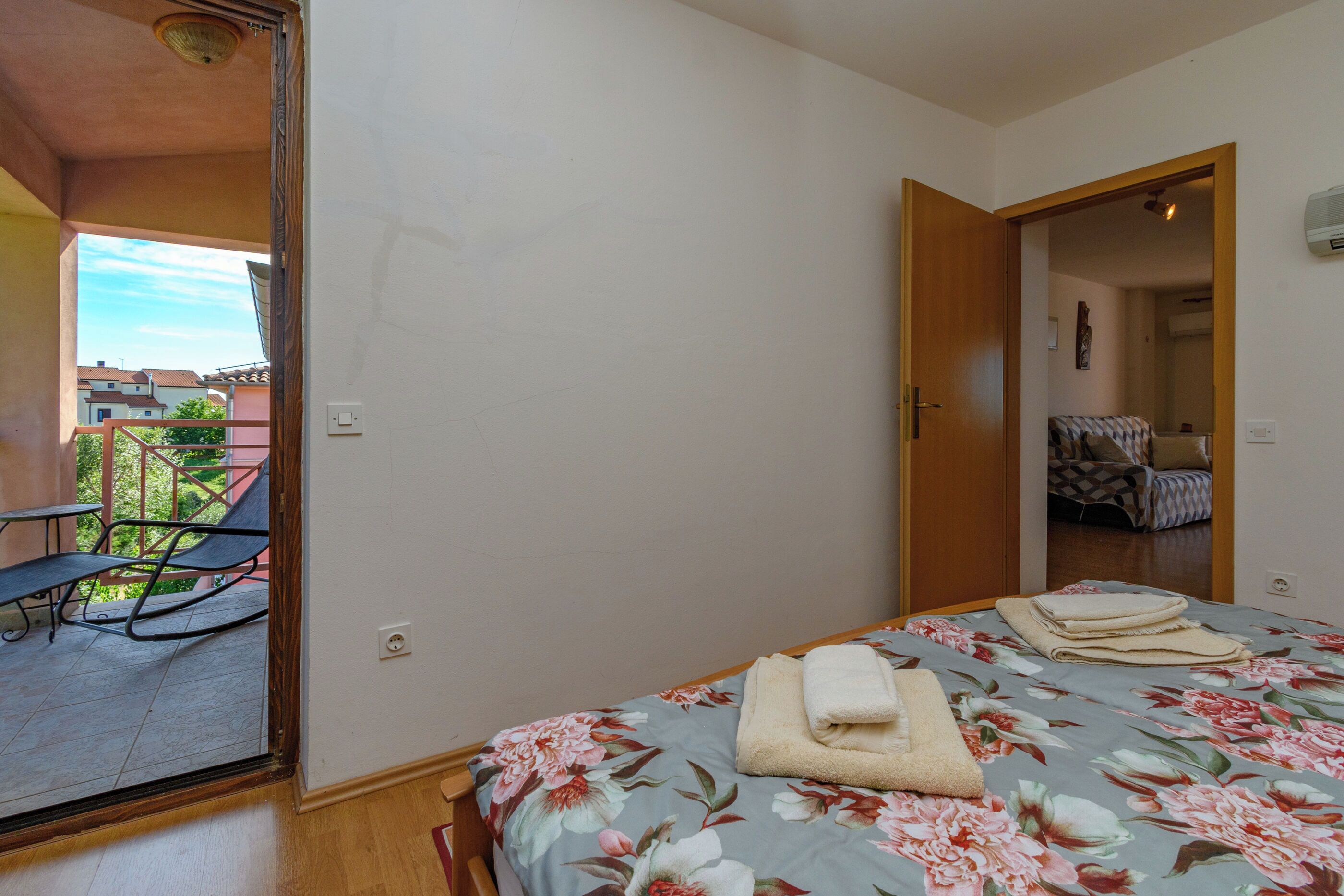 Quarto com cama, uma cadeira e vista para o exterior.