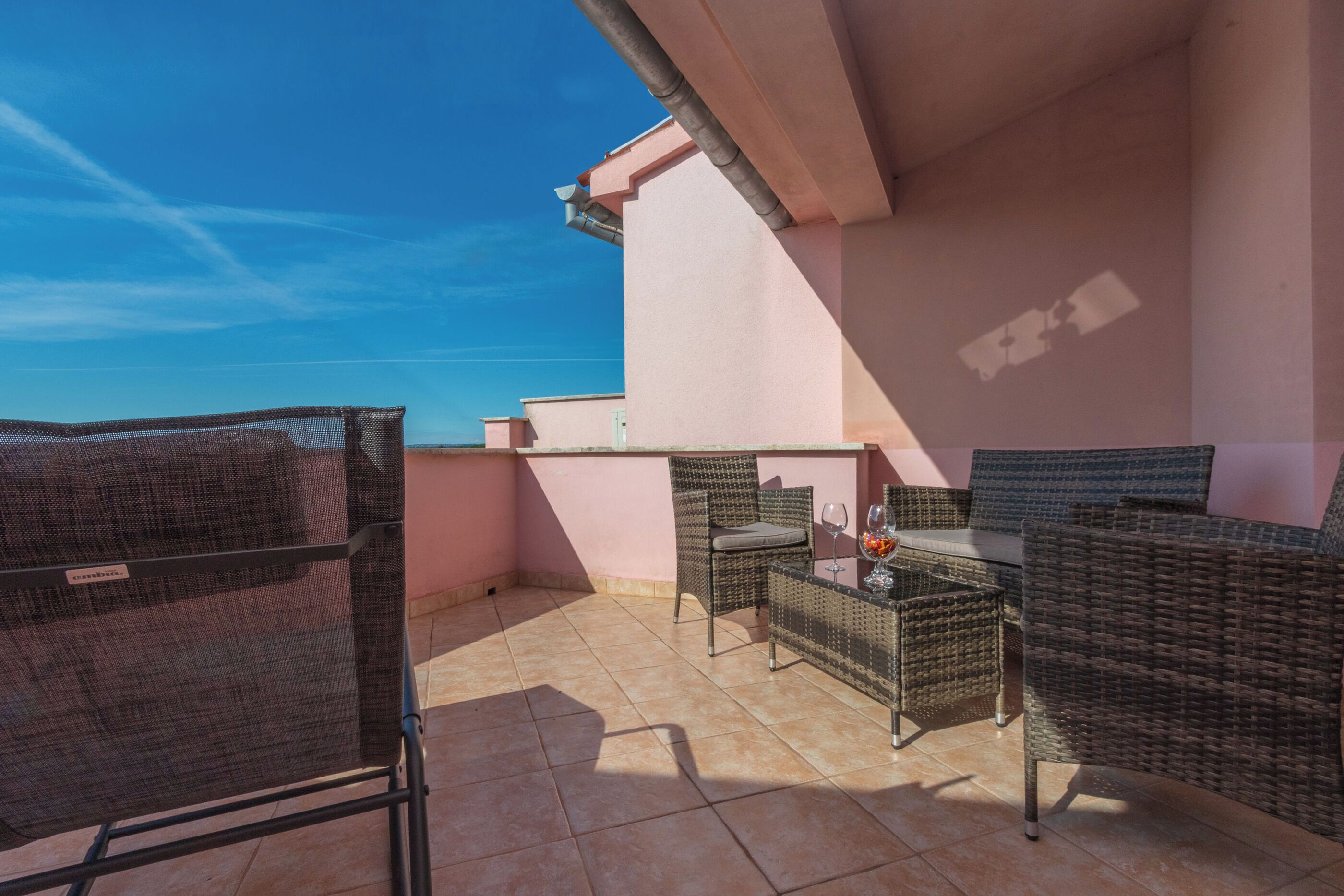 Een balkon met rieten meubels, een tafel en een stoel.