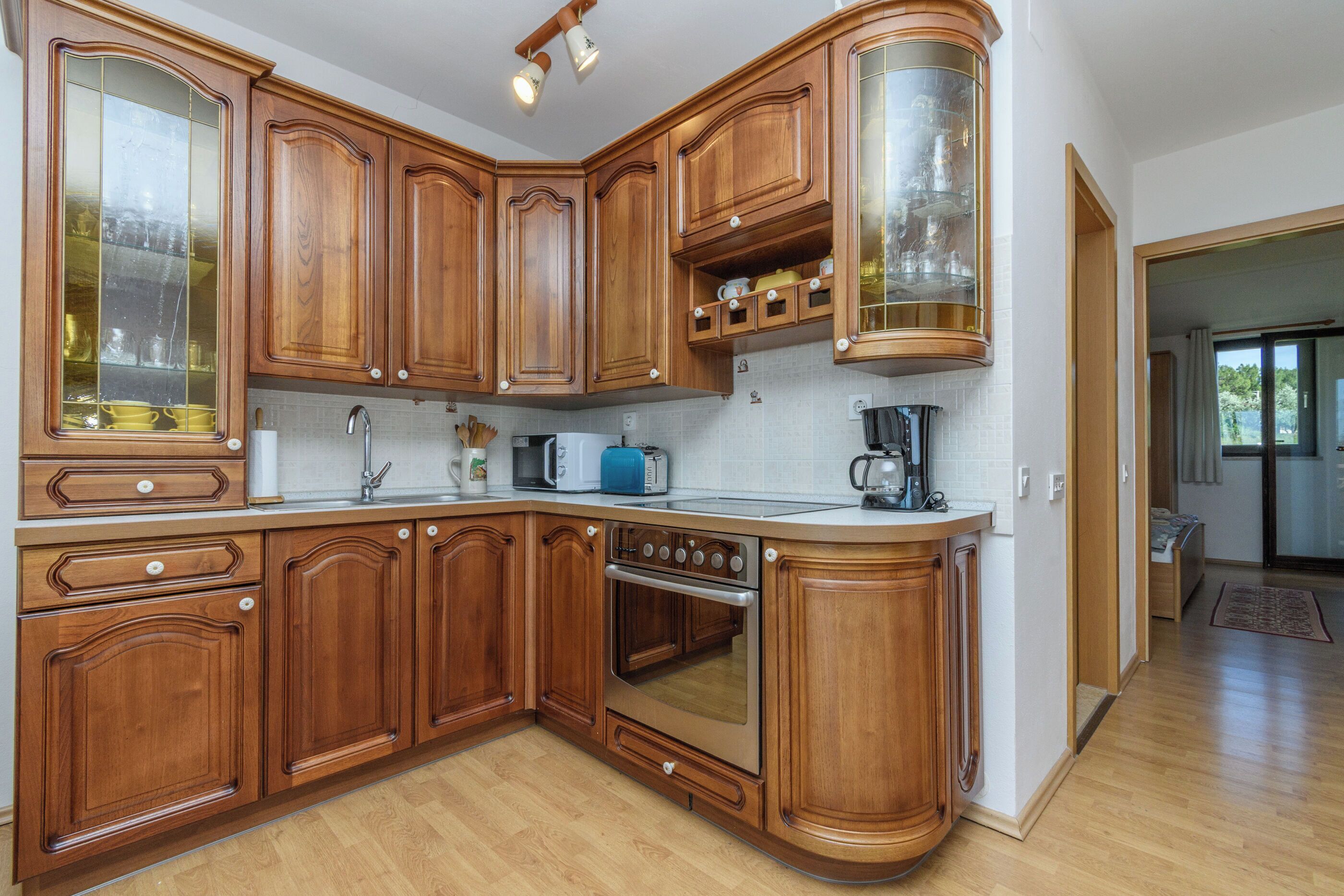 Een keuken met houten kastjes, een inbouwoven en een magnetron.