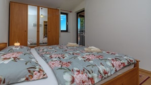 Ein Schlafzimmer mit einem Bett, einem Kleiderschrank, einem Spiegel und einem Fenster.