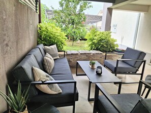 Eine Terrasse mit einer Sitzecke, Tischen und Blumentöpfen.