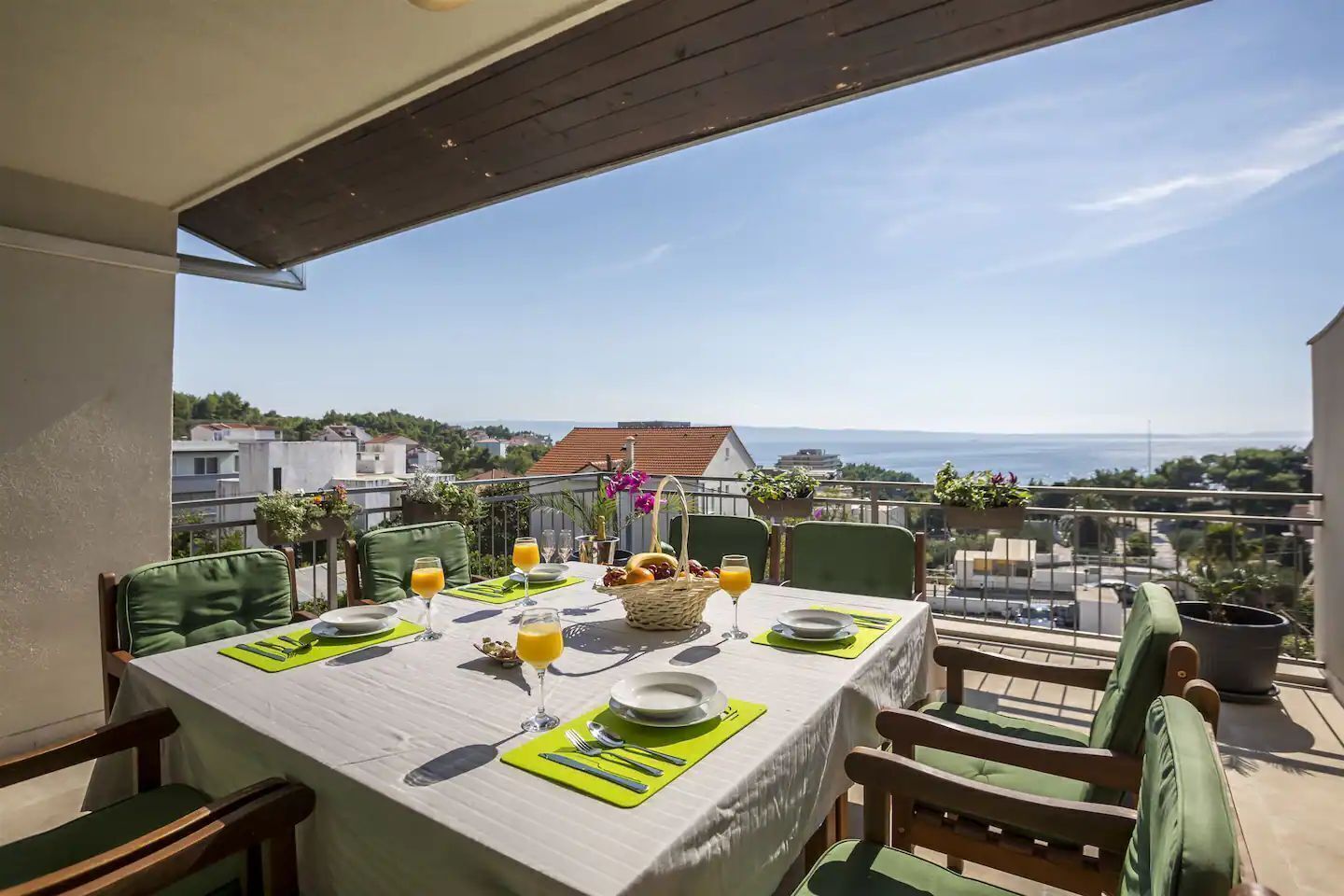 Ein Balkon mit einem für zwei Personen gedecktem Tisch, mit Blick auf Stadt und Meer.