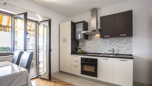 A modern kitchen with white cabinets, a built-in oven, and a large window.