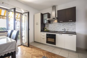 Eine moderne Küche mit weißen Schränken, einem eingebauten Ofen und einem großen Fenster.