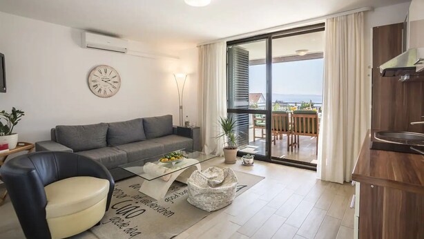 Ein modernes Wohnzimmer mit einer Couch, einem Couchtisch und Blick auf den Balkon.