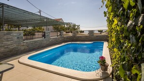 Ein Pool mit Steinmauer, überdachtem Bereich und Blick zum Himmel.