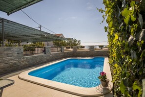Ein Pool mit Steinmauer, überdachtem Bereich und Blick zum Himmel.
