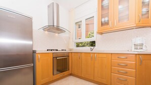 A modern kitchen with stainless steel appliances, wooden cabinets, and a window with a view. - Apartments Sunce (Okrug)