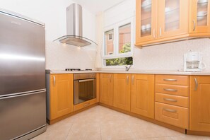 Eine moderne Küche mit Edelstahlgeräten, Holzschränken und einem Fenster mit Blick.