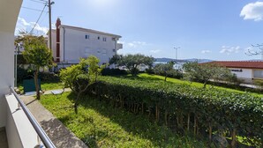 A residential building with a white facade, a red-tiled roof, and a well-maintained garden with hedges and trees. - Apartments Sunce (Okrug)