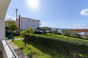 Ein Wohngebäude mit weißer Fassade, rotem Ziegeldach und einem gepflegten Garten mit Hecken und Bäumen.