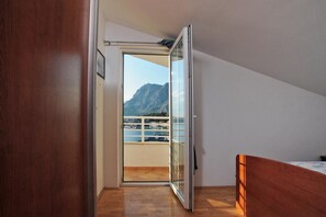 Ein Schlafzimmer mit einem hölzernen Bett, einer Schiebetür zu einem Balkon mit Blick auf die Berge.