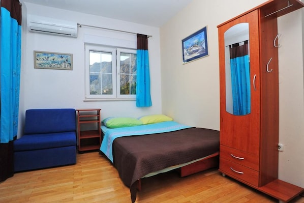 Ein Schlafzimmer mit Bett, Schrank, Sofa, Fenster und einem Bild an der Wand.