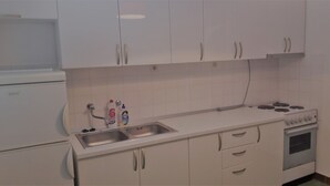 A kitchen with white cabinets, a stainless steel sink, a stove, and a dishwasher. - Apartments Oliva (Sibenik)