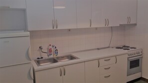 A kitchen with white cabinets, a stainless steel sink, a stove, and a dishwasher. - Apartments Oliva (Sibenik)