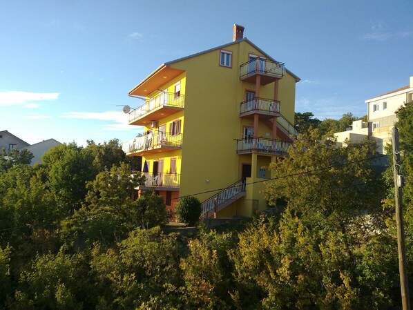A multi-story yellow building with balconies, surrounded by trees. - Apartments Panorama (Crikvenica)