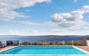 A swimming pool with a view of the sea and distant hills. - Apartments Panorama (Crikvenica)