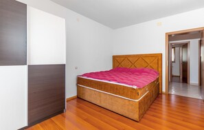 A bedroom with a wooden bed, white walls, and a wooden floor. - Apartments Panorama (Crikvenica)