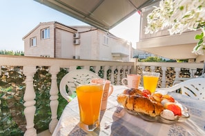 Ein Balkon mit einem Frühstückstisch, komplett mit Croissants und einem Glas Orangensaft.