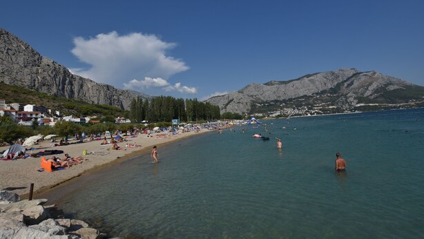 A beach with clear water, rocky mountains, and a few people. - Apartments Neda (Dugi Rat)