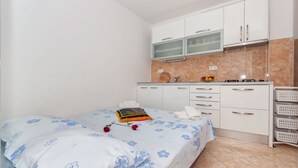 A bedroom with a bed, a nightstand, a small table, and a window. - Apartments Neda (Dugi Rat)