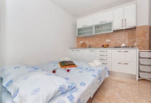 A bedroom with a bed, a nightstand, a small table, and a window. - Apartments Neda (Dugi Rat)