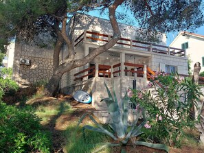 A stone building with a balcony, surrounded by trees and plants. - House Beachouse Natural Park (Selca)