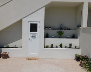 A white door with a sign indicating WC facilities, a small potted plant, and a stone sculpture on a shelf. - Apartment Zeljko (Primosten)