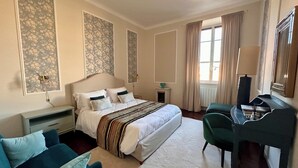 Een slaapkamer met een bed, bureau, stoel, nachtkastje en raam met gordijnen.