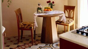 Een keuken met een betegelde achterwand, een houten tafel met stoelen, een hangplant en een gasfornuis.