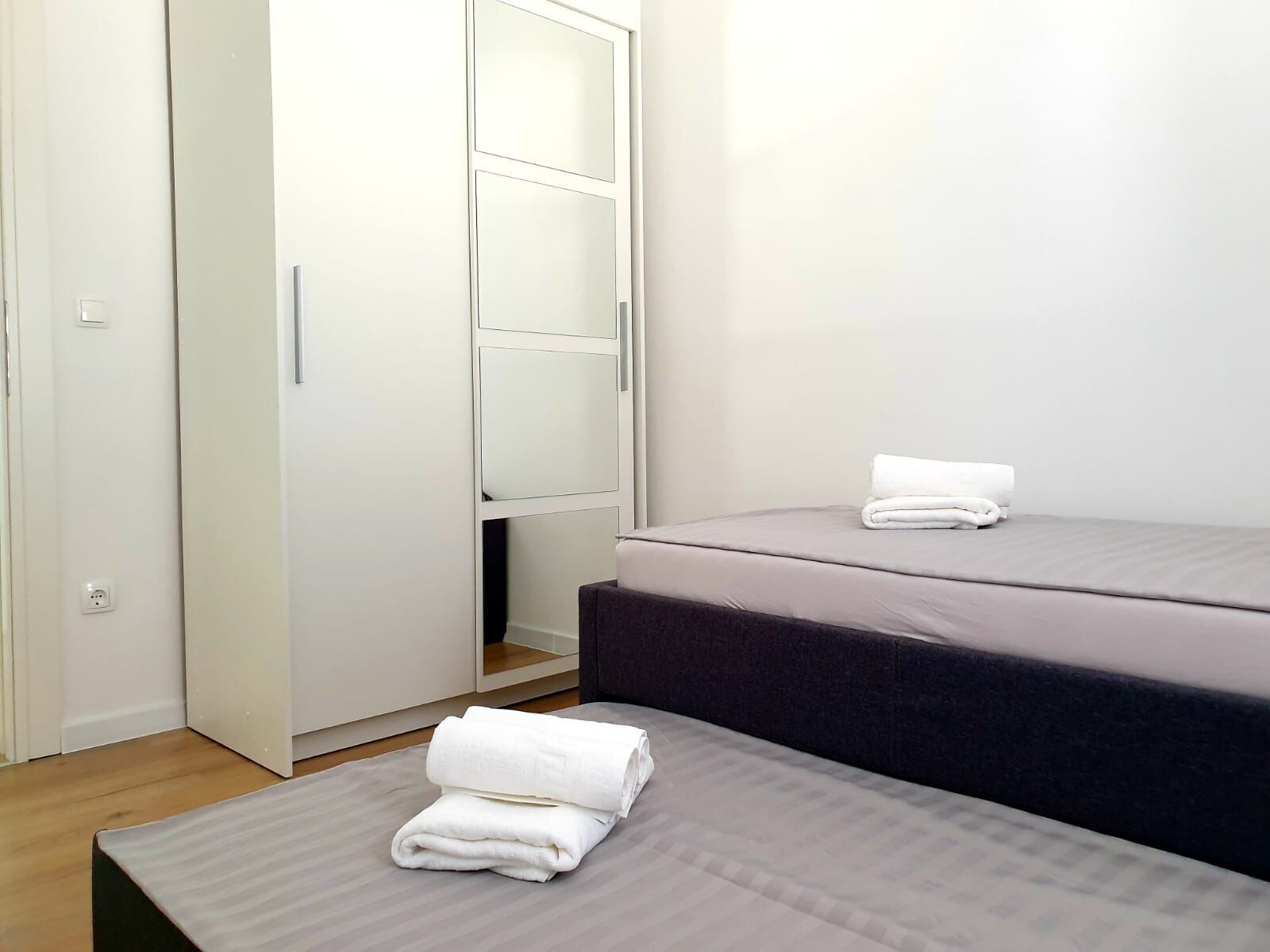 Une chambre avec deux lits, une armoire et une petite table avec des serviettes.