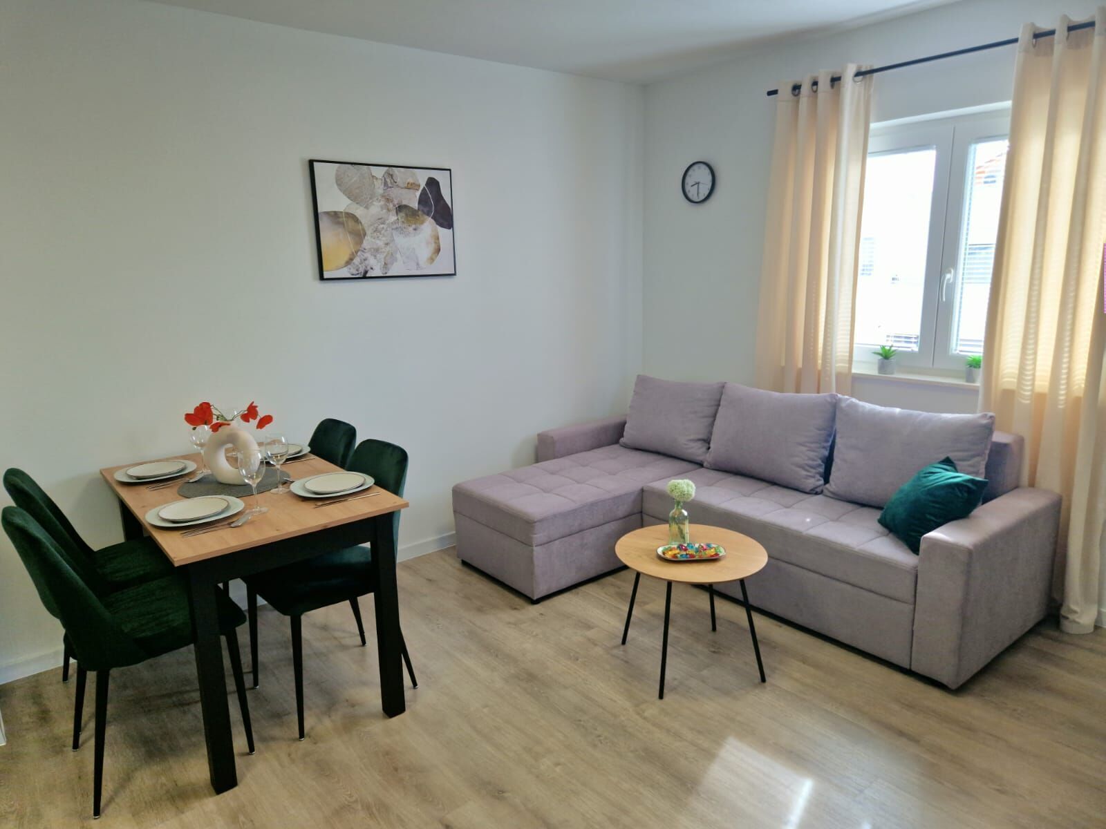 A modern living room with a dining area, a sofa, a coffee table, and a clock on the wall.