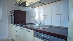 A modern kitchen with a built-in oven, a dishwasher, and a stainless steel sink. - Apartment Kaleta (Rogoznica)