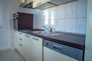 A modern kitchen with a built-in oven, a dishwasher, and a stainless steel sink. - Apartment Kaleta (Rogoznica)