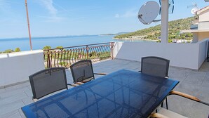 A balcony with a table and chairs, a satellite dish, and a view of the sea. - Apartment Kaleta (Rogoznica)