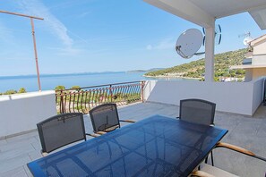 A balcony with a table and chairs, a satellite dish, and a view of the sea. - Apartment Kaleta (Rogoznica)