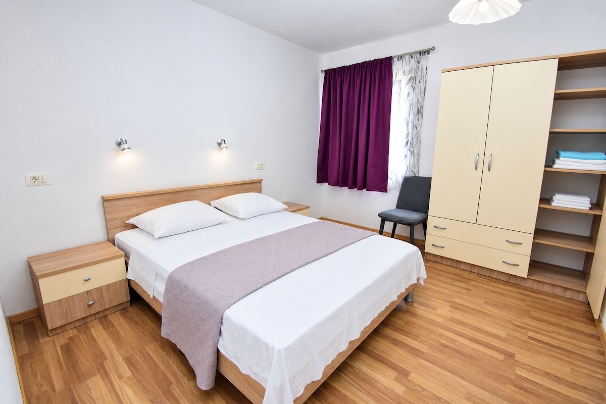 A bedroom with a bed, bedside tables, a wardrobe, and a chair.