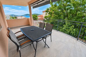 A balcony with a table and chairs, a view of the sea, and a railing. - Apartment Kaleta (Rogoznica)